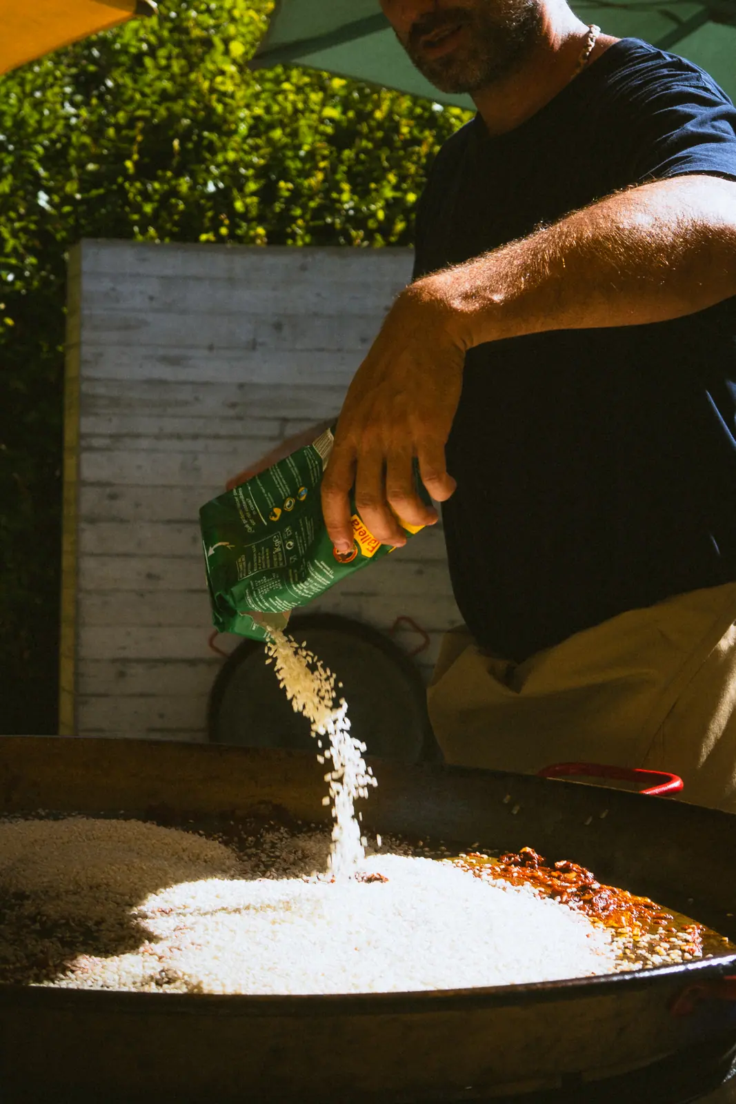 Food photography Zürich — chef pouring rice into a paella pan